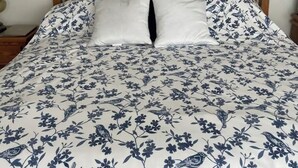 A bed with a floral-patterned duvet, a wooden headboard, and a wall-mounted bird decoration.