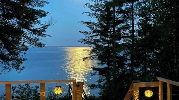 A wooden deck with a view of the ocean and a full moon.