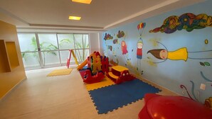 A children's play area with a slide, climbing structure, and colorful wall art. - Bela Hospedagem - Jd do Atlântico 402B (João Pessoa)