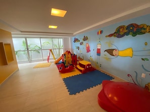 A children's play area with a slide, climbing structure, and colorful wall art.