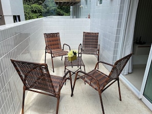 A balcony with four wicker chairs and a small table, surrounded by white tiled walls.