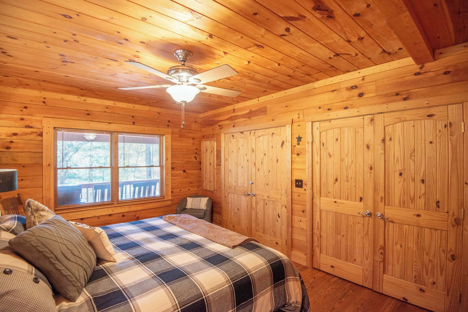 Une chambre confortable dans un chalet, avec un lit, un ventilateur de plafond et des murs en bois.