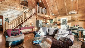 A spacious log cabin interior with a living area, a dining area, and a kitchen.