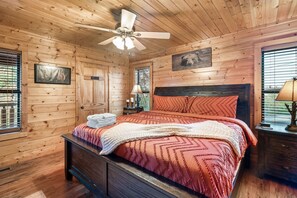 A wooden cabin bedroom with a bed, a ceiling fan, a private sign, and a window with blinds.
