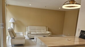 Ein modernes Wohnzimmer mit einer Couch, einem Sessel und einer Holzkommode.