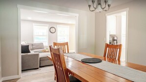 A dining area with a wooden table and chairs, a grey rug, and a chandelier. - Modern Self check-inLarge Fenced Yard A/C Close to Everything Quiet Neighborhood (Olympia)