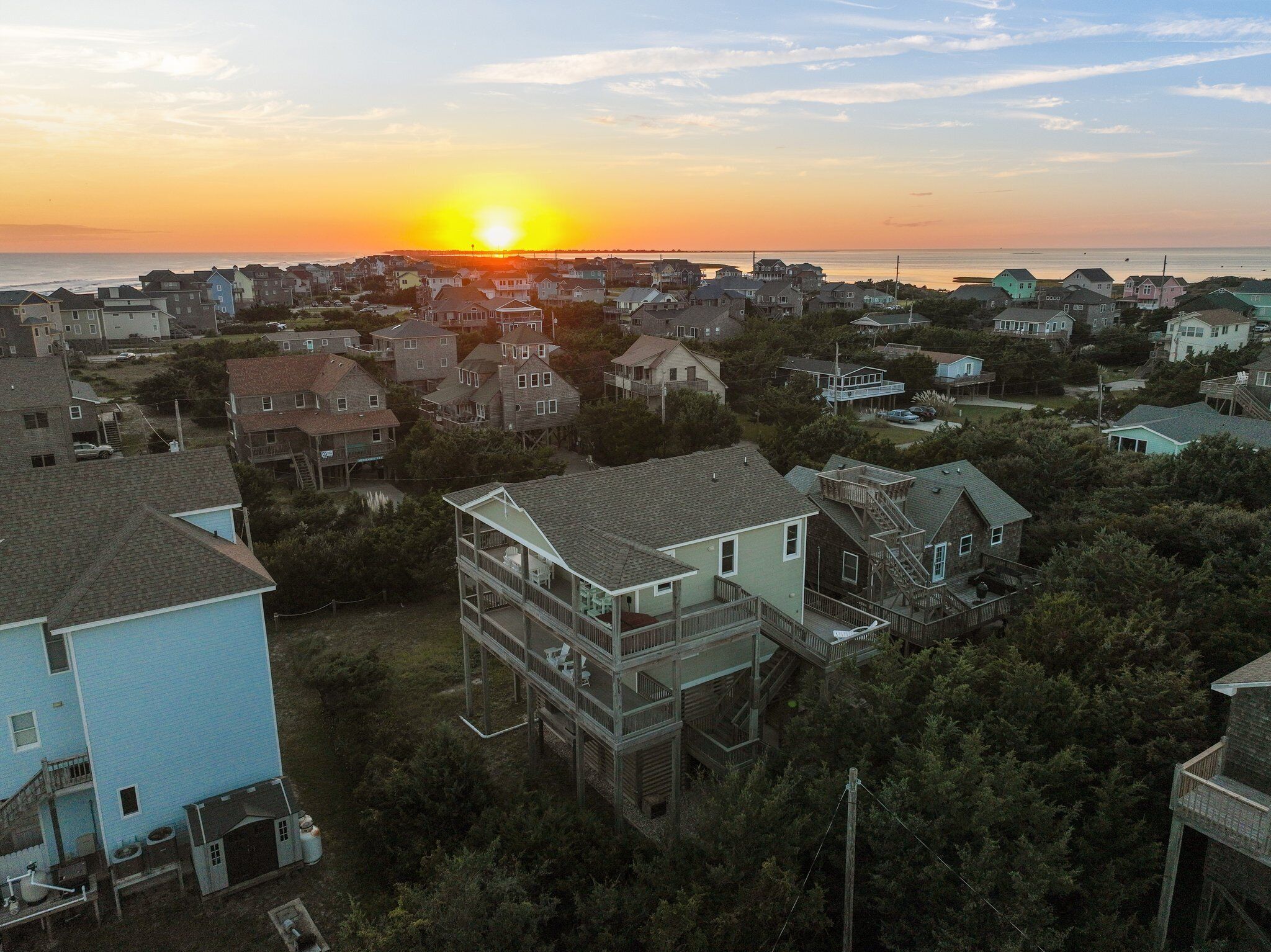 Un quartier résidentiel avec des maisons et une vue sur le coucher de soleil sur l’océan.