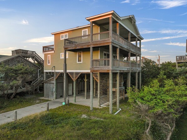 A two-story house with a balcony on the upper floor, a staircase leading to the upper level, and a wooden deck. - Oceanside, Steps to the Beach, Hot Tub, Pet Friendly, Ocean and Sound Views (Frisco)