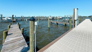 A wooden pier extending into a body of water with boats docked at the far end.