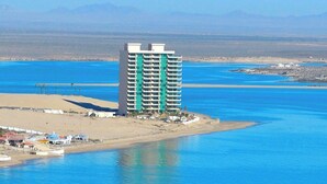 A high-rise hotel with multiple floors, situated near a body of water.