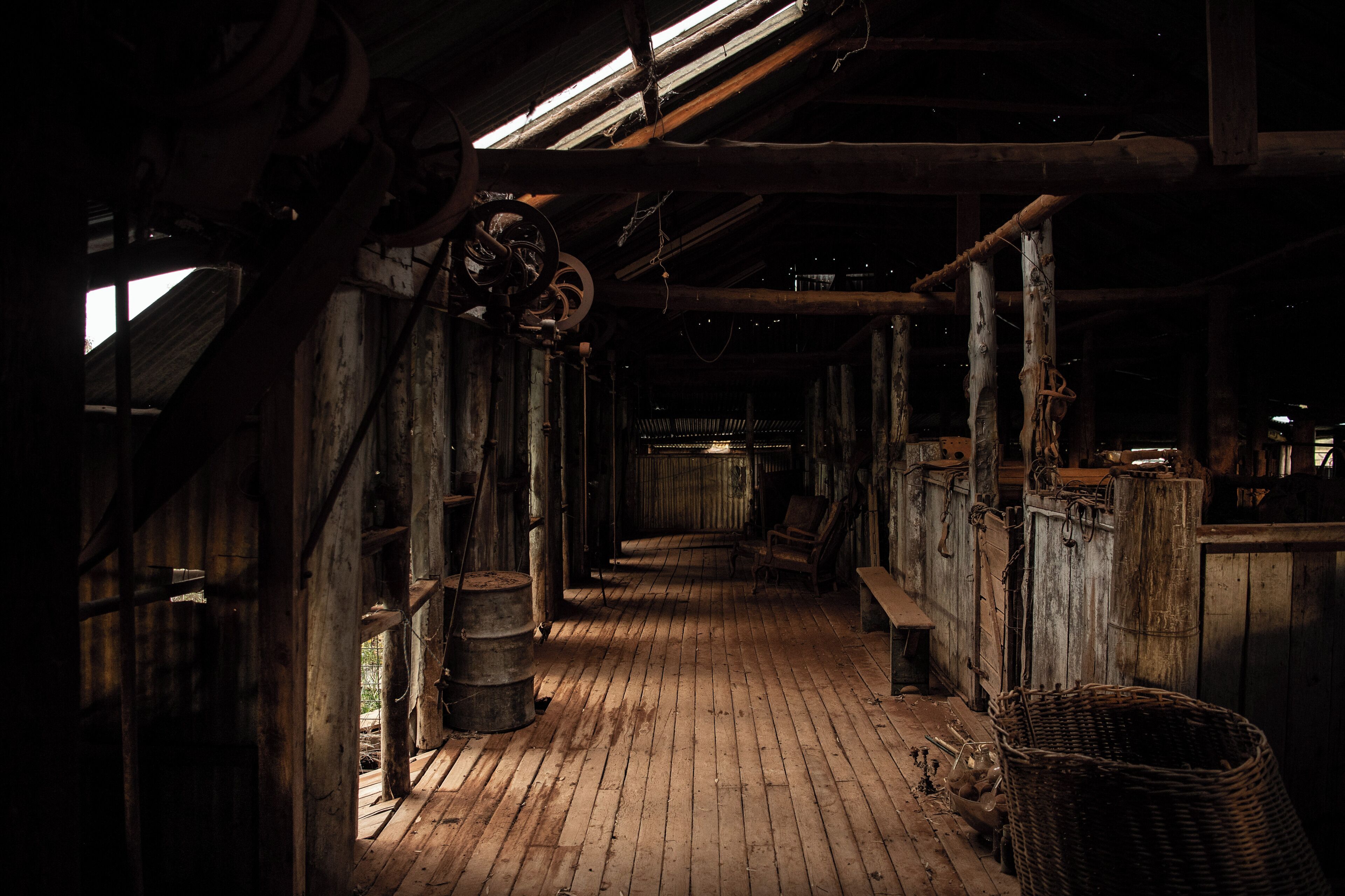 A dimly lit wooden interior with a rustic ambiance, featuring a wooden floor, beams, and a bench.