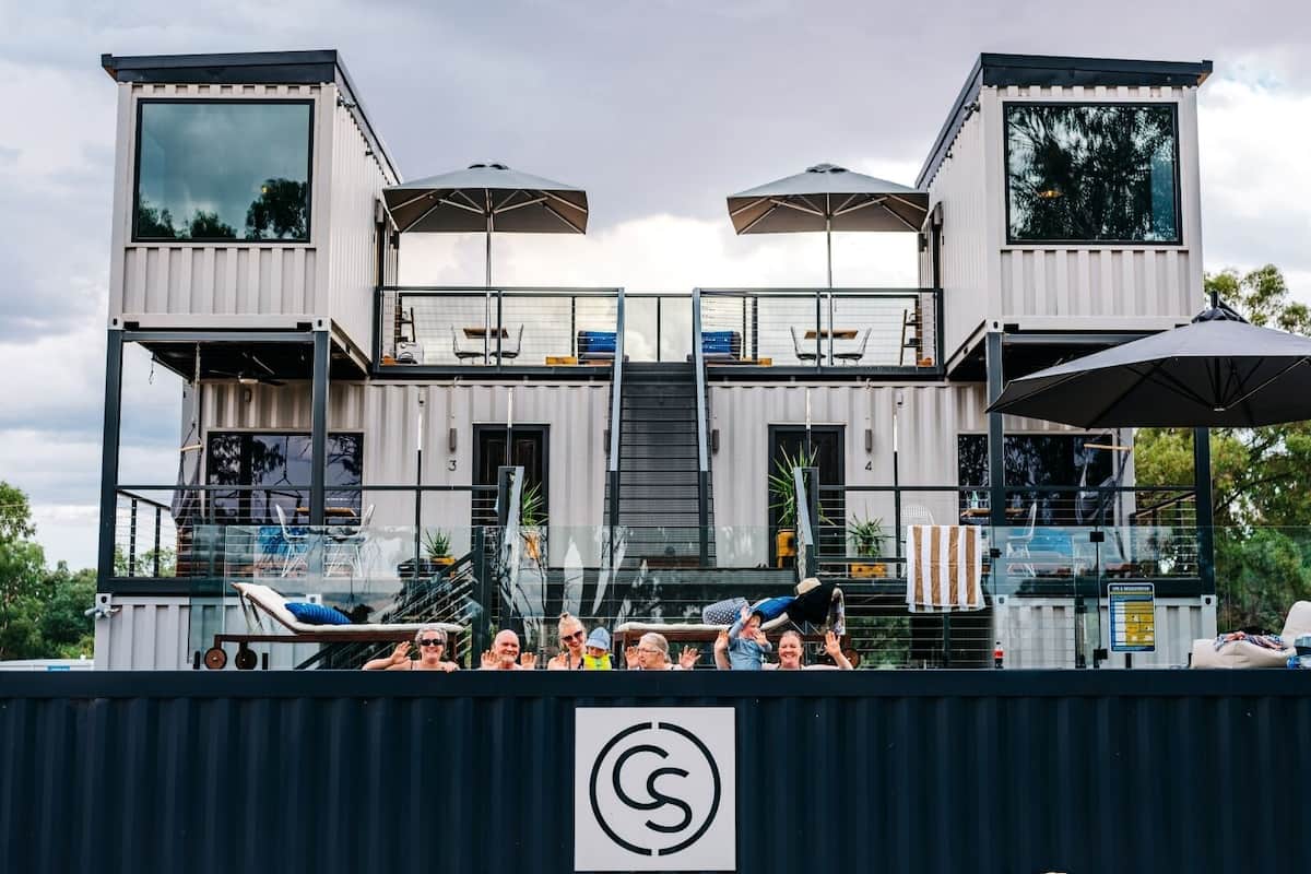 A modern, multi-level container house with outdoor seating and a pool.