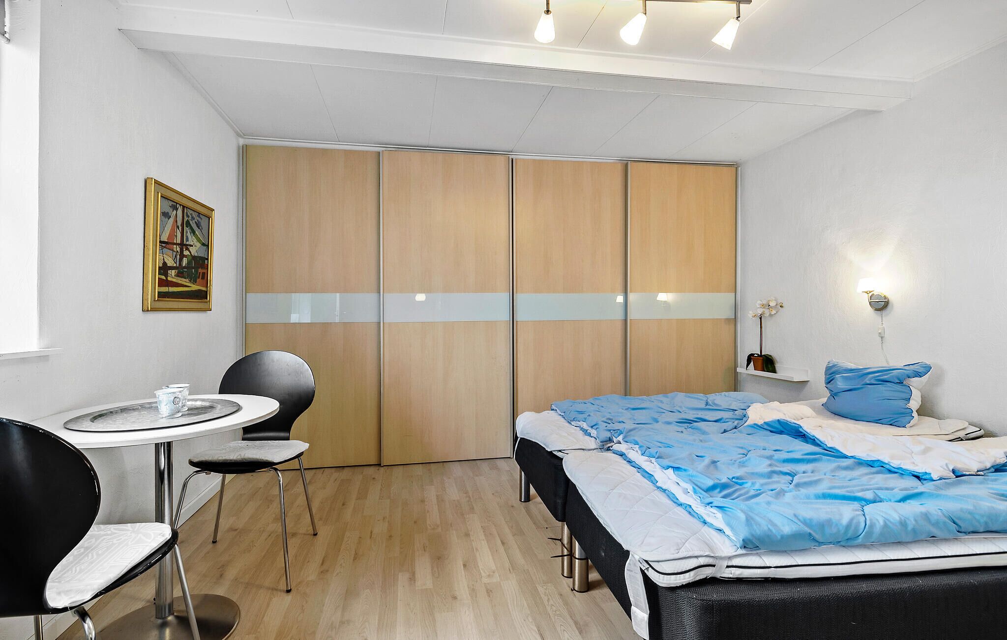 A bedroom with a bed, a desk, a chair, and a wardrobe.