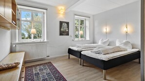 A bedroom with two beds, a radiator, a window with a view of trees, and a framed wildlife picture on the wall. - 5 bedroom lovely home in Aakirkeby (Aakirkeby)