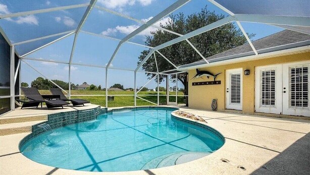 Una piscina techada con sillas de descanso, un porche cubierto y vistas del paisaje circundante.