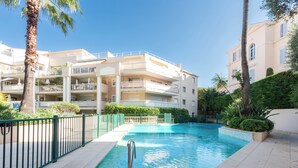 A swimming pool surrounded by a fence, with a multi-story building in the background. - A-Br – Quiet, Infinity Pool & Private Parking (Cannes)