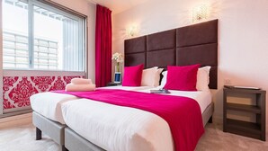 A hotel room with a large bed, a nightstand, a window with blinds, and a wall-mounted light fixture. - Chambre Parfaite pour des Vacances de Ski de Rêve! (Courchevel)