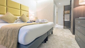 Ein Hotelzimmer mit einem großen Bett, einem Nachttisch, einer Lampe und einem Kleiderschrank.