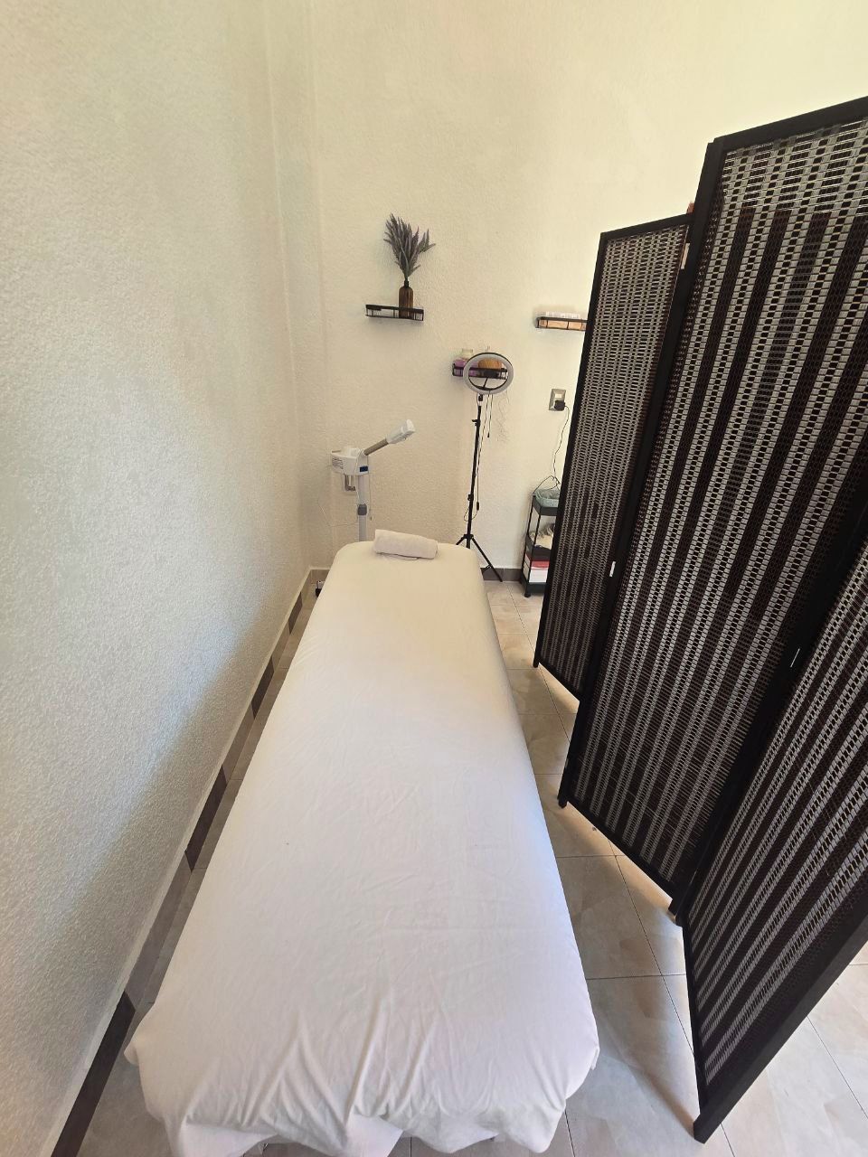Une petite chambre privée avec un lit simple, un sèche-cheveux, un miroir et une petite étagère contenant des articles de toilette.