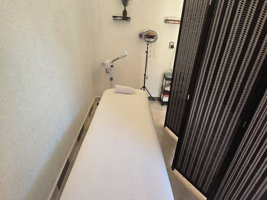 Una habitación pequeña y privada con una cama individual, un secador de pelo, un espejo y un estante pequeño con artículos de aseo.