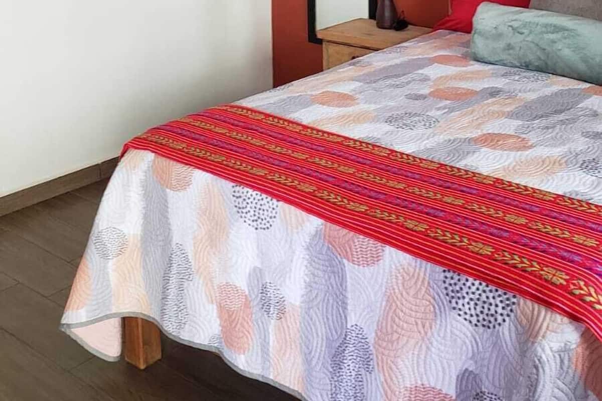 A bedroom with a bed, a wooden headboard, a mirror, and decorative wall art.