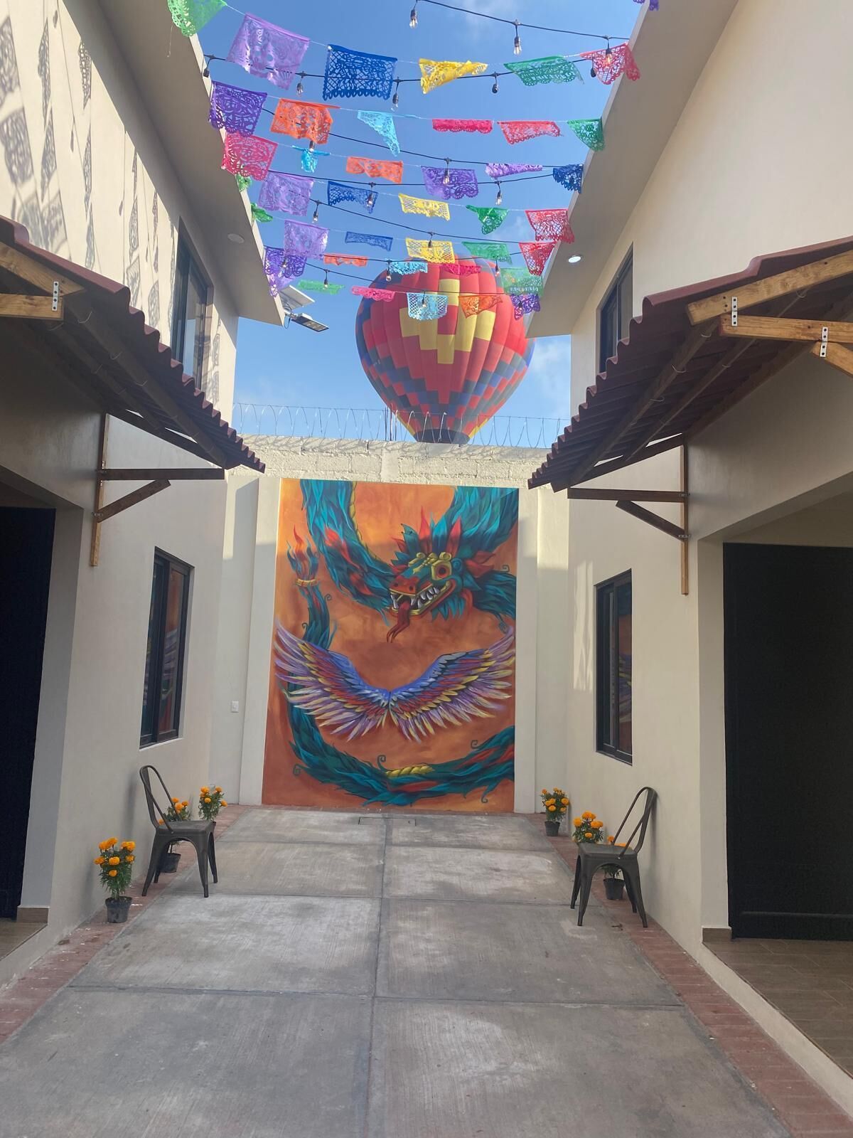 Un patio con un mural colorido de un dragón, luces colgantes y un globo aerostático.