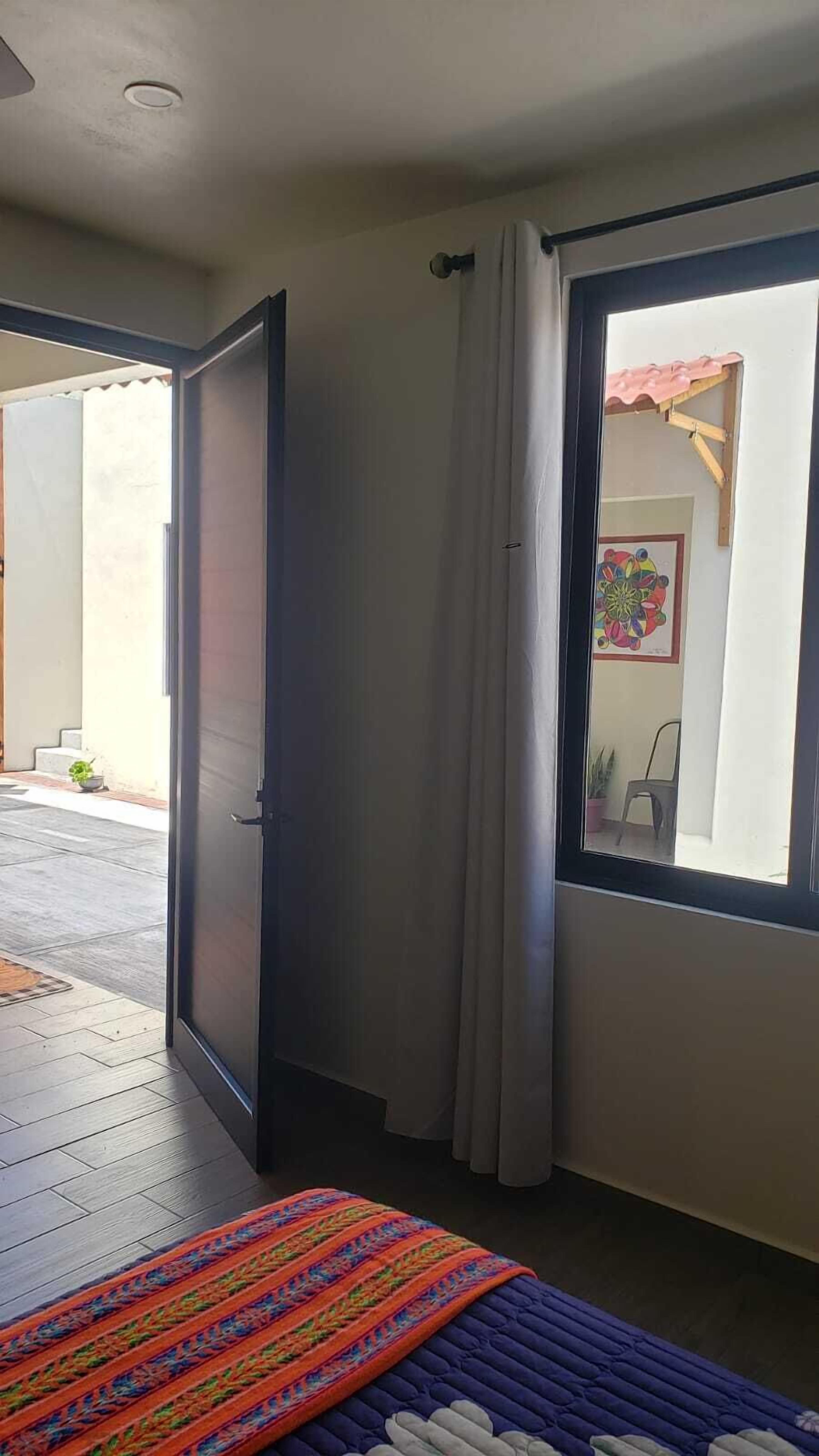 Ein Zimmer mit Bett, einem Vorhangfenster und einer Tür, die nach draußen führt.