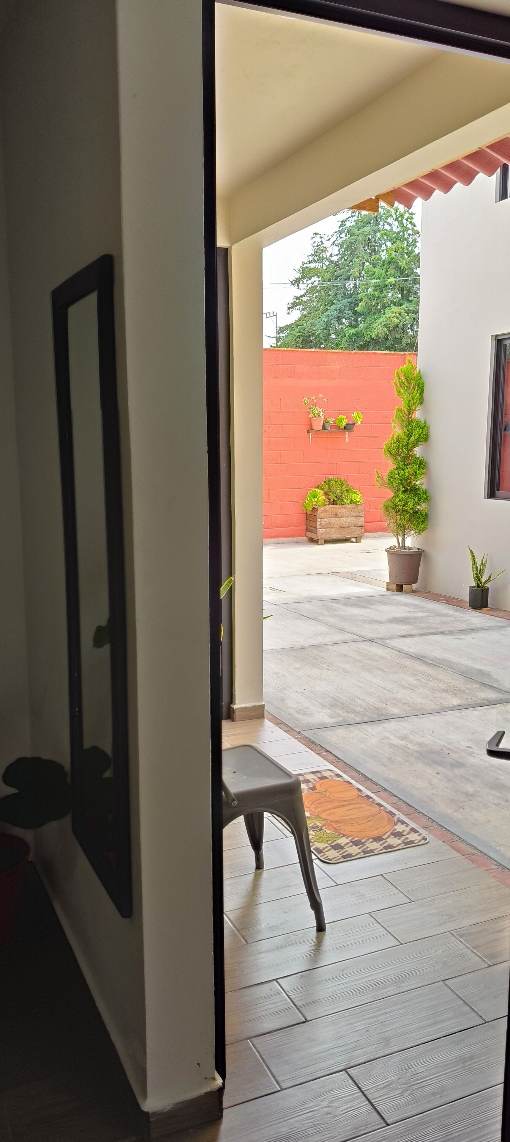 A doorway leading to an outdoor area with a tiled floor, a small bench, and potted plants.