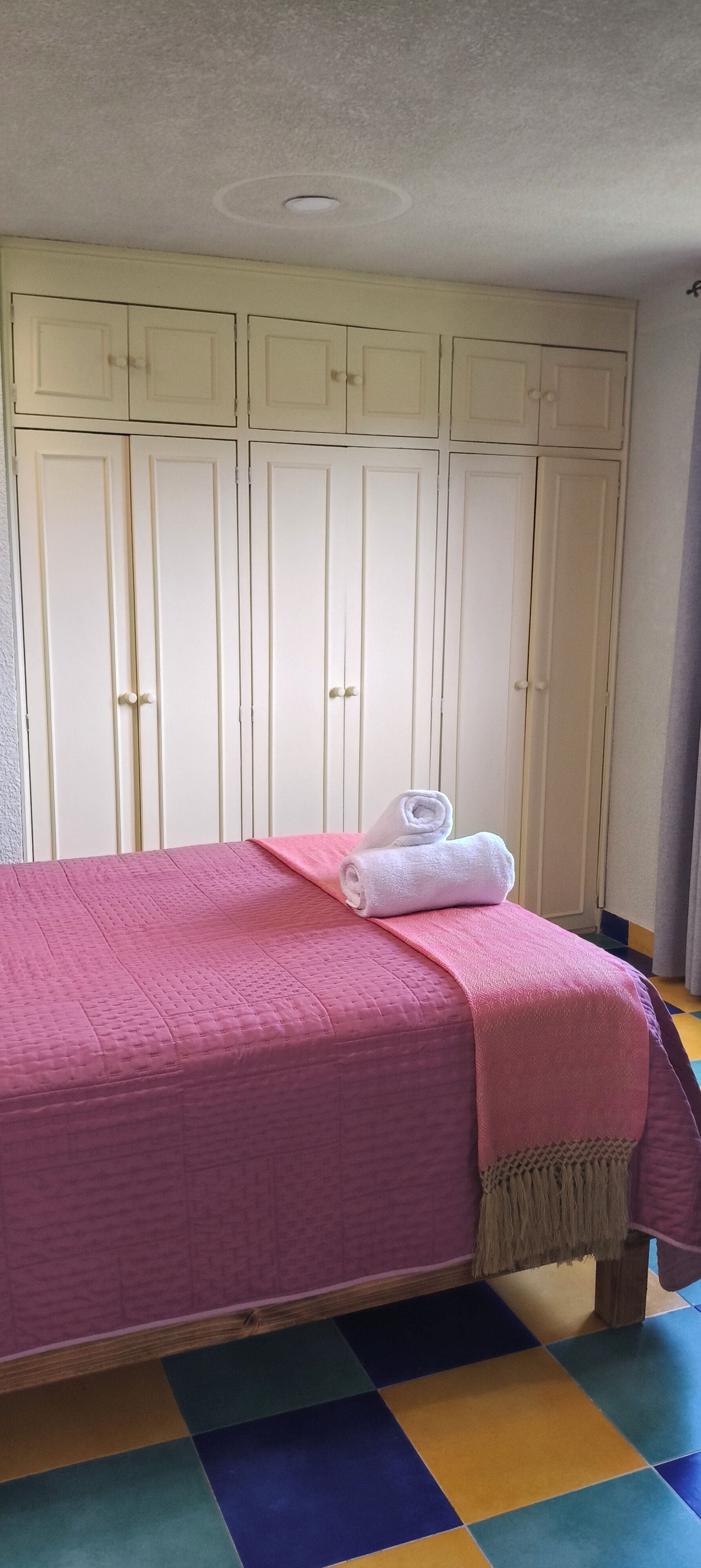 Una habitación con cama, armario y piso colorido.