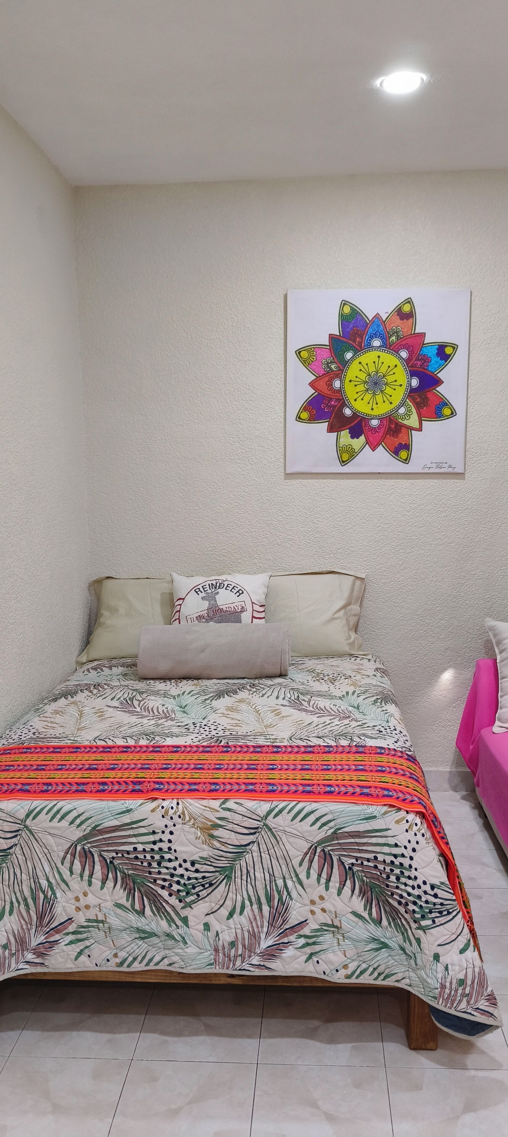 A bedroom with a bed, pillows, and a colorful artwork on the wall.