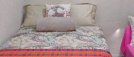 A bedroom with a bed, pillows, and a colorful artwork on the wall.