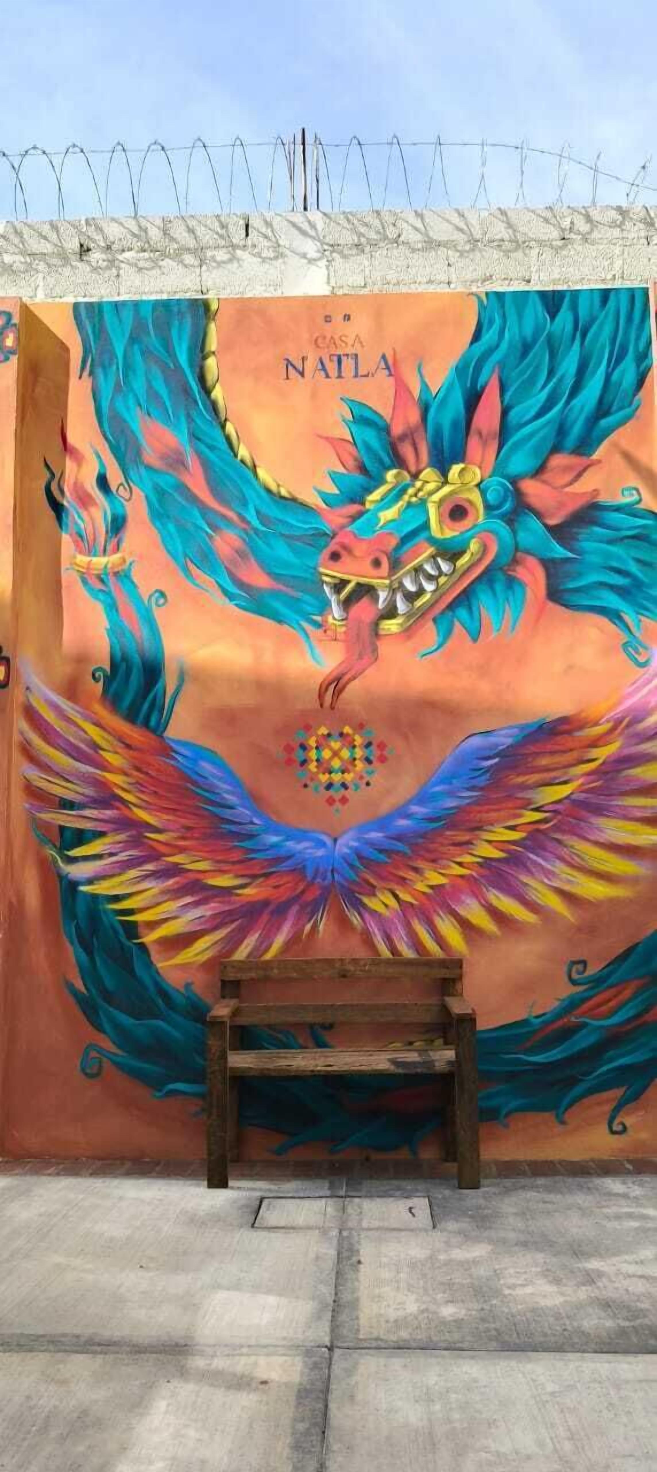 A mural of a colorful dragon with a bench in front.