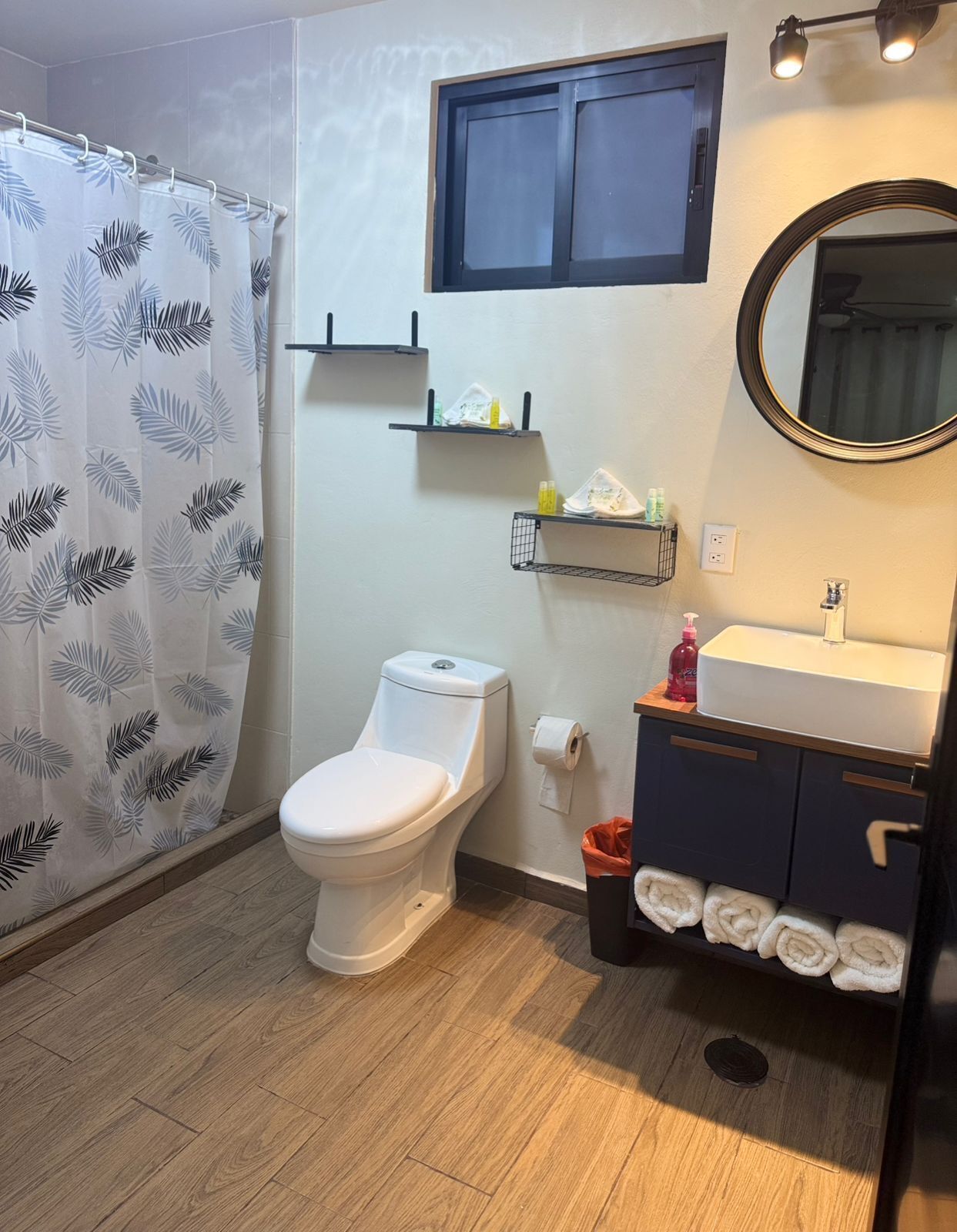 A bathroom with a toilet, a sink, a mirror, and a shower curtain.