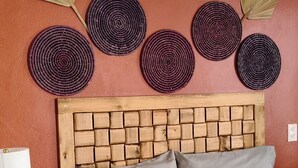 Un lit bien fait, avec une couverture à motifs, une tête de lit en bois et une table de chevet surmontée d’une lampe.