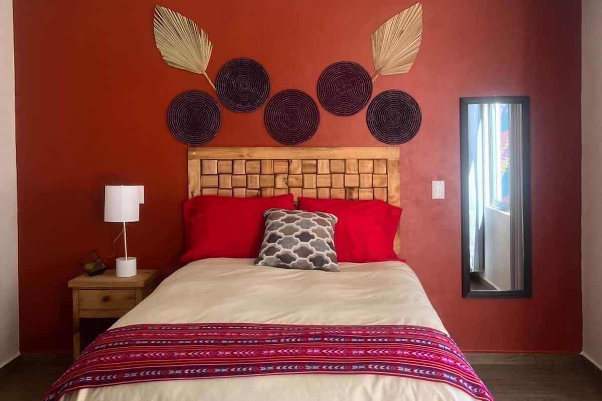 A bedroom with a wooden bed, red walls, a ceiling fan, and decorative wall art.