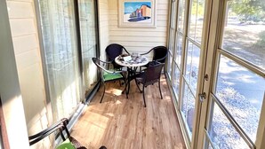 A sunlit room with a ceiling fan, a framed picture on the wall, and a table with chairs.