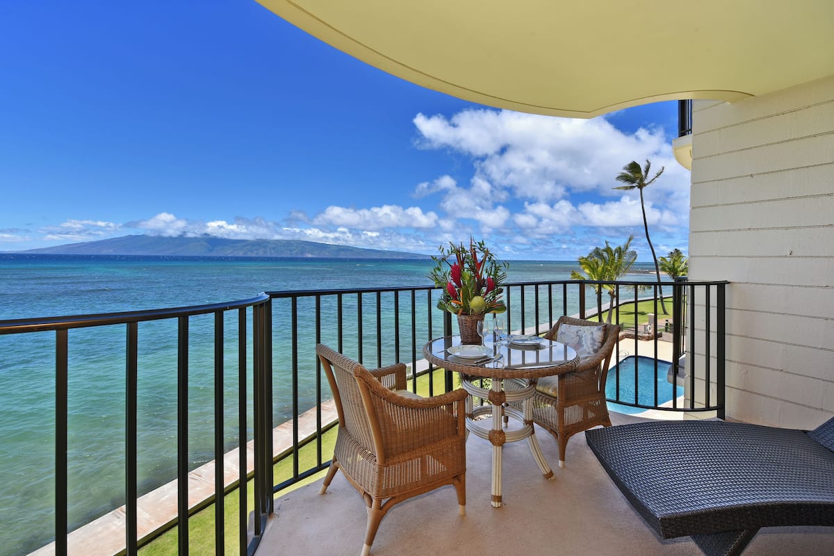 Un balcon avec vue sur l’océan, une table avec des chaises et une petite piscine.
