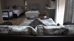 A bedroom with two beds, a dresser, and a television. - The Old Mill Bed & Breakfast (Biggar)