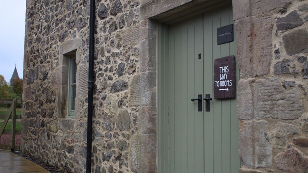A stone building with a green door and a sign that reads "THIS WAY TO ROOMS". - The Old Mill Bed & Breakfast (Biggar)