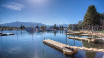 Un port de plaisance avec des bateaux amarrés, un ciel dégagé et des montagnes en arrière-plan.