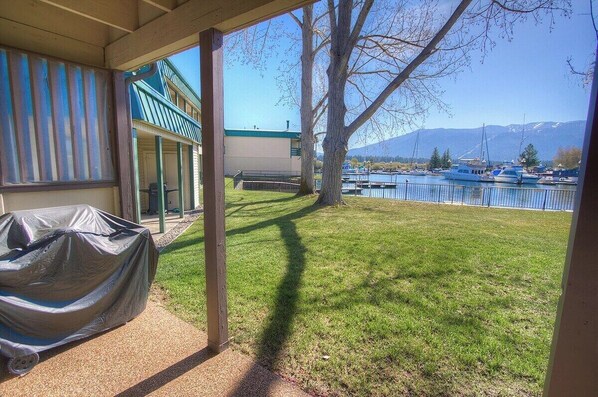 A covered patio with a view of a marina and mountains.