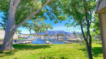 A marina with boats docked, surrounded by trees and a mountain backdrop.