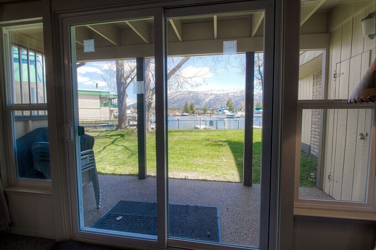 A sliding glass door leading to a backyard with a grassy area, a tree, and a view of mountains.