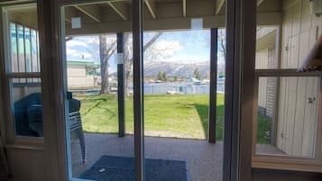 A sliding glass door leading to a backyard with a grassy area, a tree, and a view of mountains.