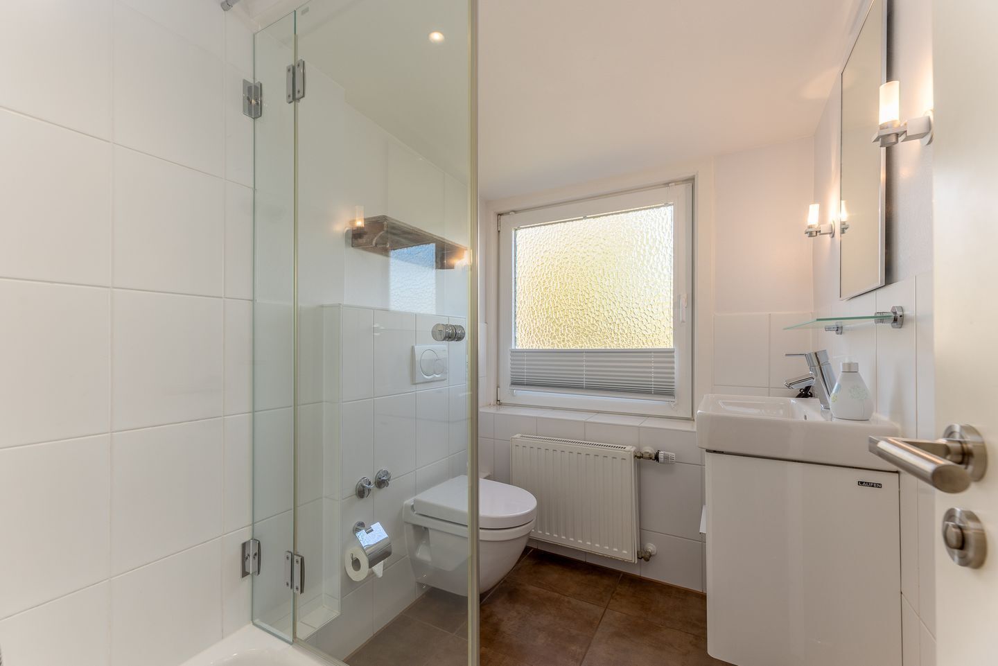 Une salle de bain moderne avec une douche à parois de verre, des toilettes, un lavabo et une fenêtre équipée de stores.