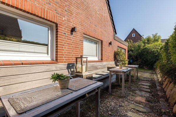A patio area with wooden benches and tables, a potted plant, and a lantern.