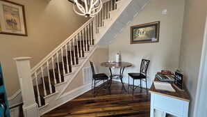 A staircase with white railings and wooden steps, a dining area with a round table and chairs, and a fireplace with books and a sign. - Shire-Southern-Comfort quiet 3-bedroom house w/WiFi and AC in heart of downtown  (Frankfort)