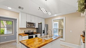 A modern kitchen with white cabinets, a wooden countertop, stainless steel appliances, and a large window. - Shire-Southern-Comfort quiet 3-bedroom house w/WiFi and AC in heart of downtown  (Frankfort)