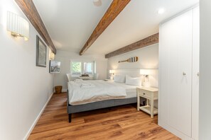 Ein Schlafzimmer mit Bett, Nachttischen, einem Kleiderschrank und einem Fenster mit Tageslicht.