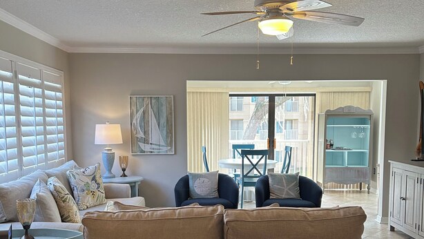 Een woonkamer met een bank, een eettafel en een plafondventilator.